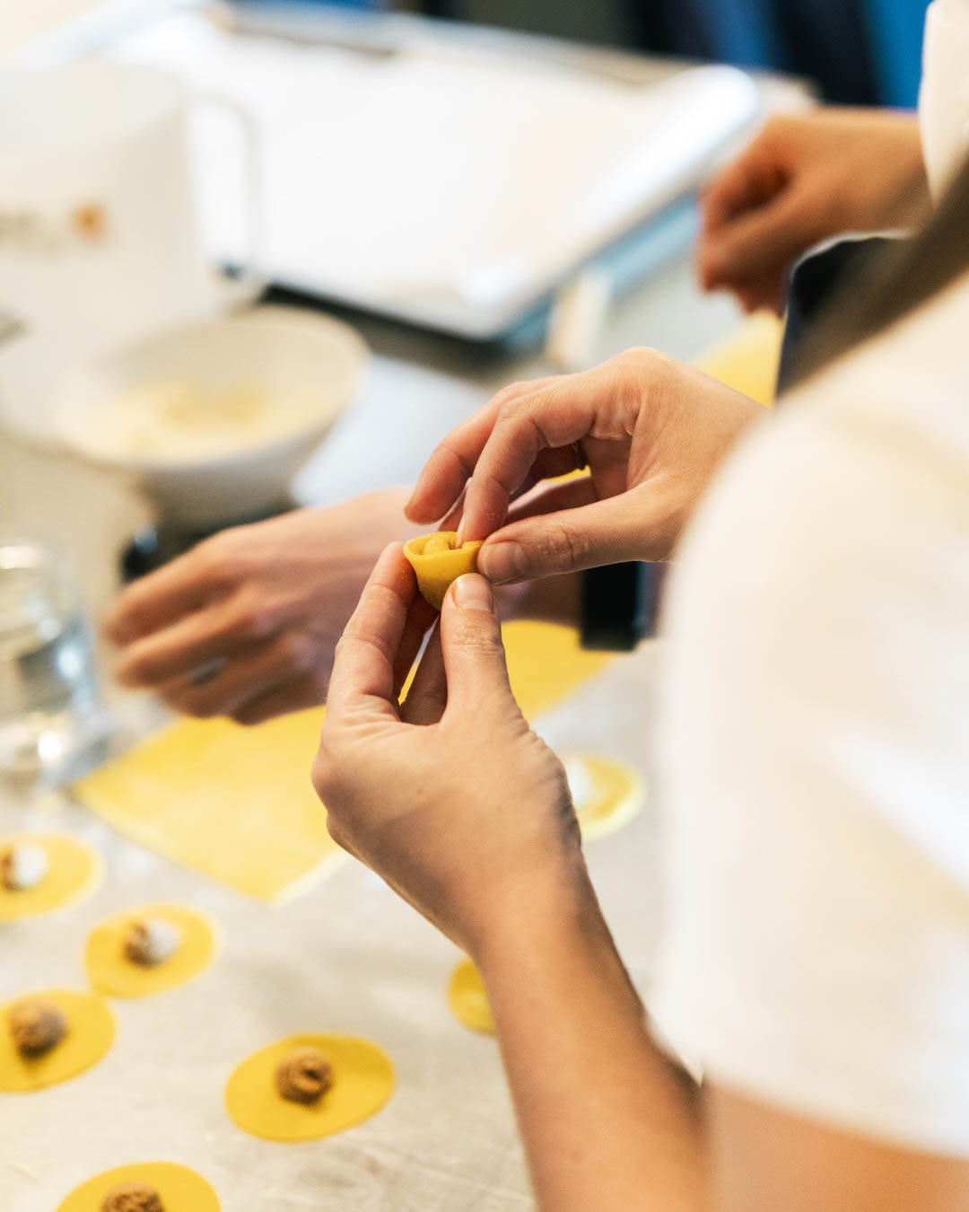 Preparazione artigianale di pasta fresca durante un evento pugliese